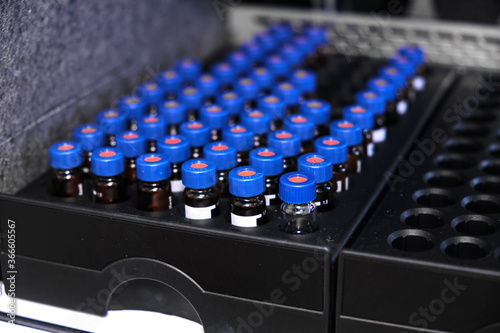 Glass vials with blue caps are in the rack of HPLC system with autosampler. Separation of compounds at chemical or clinical laboratory. Scientific and research work. Development of pharmaceuticals.