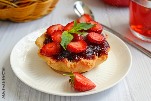 Appetizing cake with juicy ripe strawberries and mint leaves on a white plate