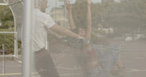 Couple playing with shopping trolley in car park and having fun together photo