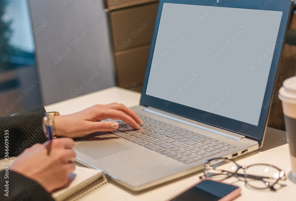 close-up of the hand of a business woman who works on a laptop and writes information into a notebook. The concept of distance learning, freelancing and working online close-up of the hand of a business woman who works on a laptop and writes information into a notebook. The concept of distance learning, freelancing and working online