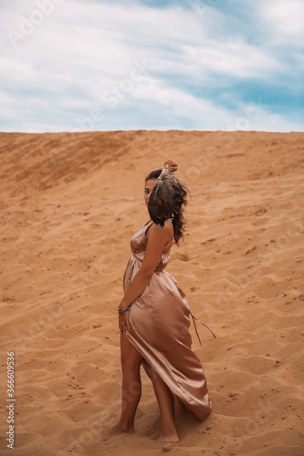 Dark girl with voluminous curly hair among the Sands in the sand dune