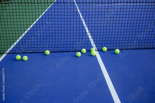 tennis balls and net on court © Katsiaryna