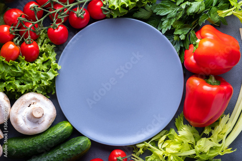 Fresh vegetables around empty plate. Organic food. Ingredients. Copy space, top view