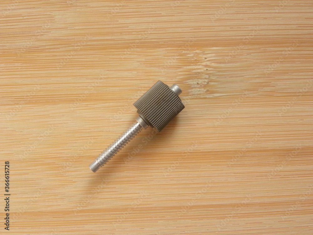 Small cylindrical metal screw kept on wooden table Small cylindrical metal screw kept on wooden table