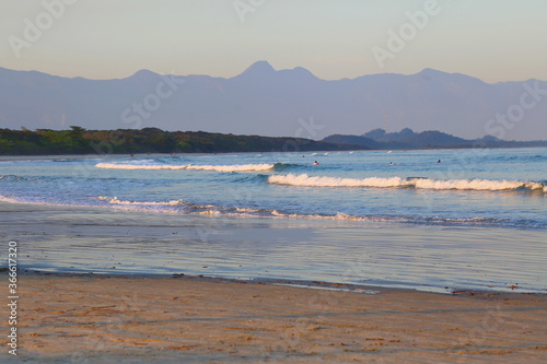 Fototapeta Naklejka Na Ścianę i Meble -  Blue ocean with calm waves. In the background vegetation and far away mountains.  Itaguare beach, Bertioga, Brazil 