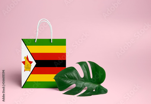 Zimbabwe shopping concept. National cardboard shopping bag with monstera leaf and pink background. Online shopping theme. photo