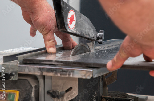 a man cuts tiles on a special machine with a metal circle