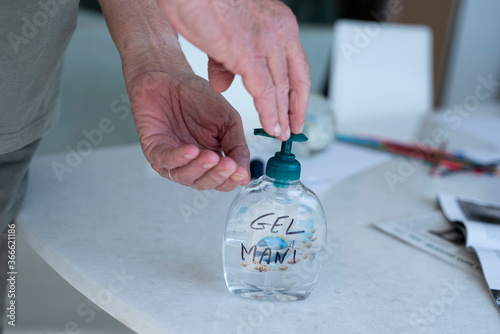 mani di anziano che si disinfetta con gel antibatterico durante il covid photo
