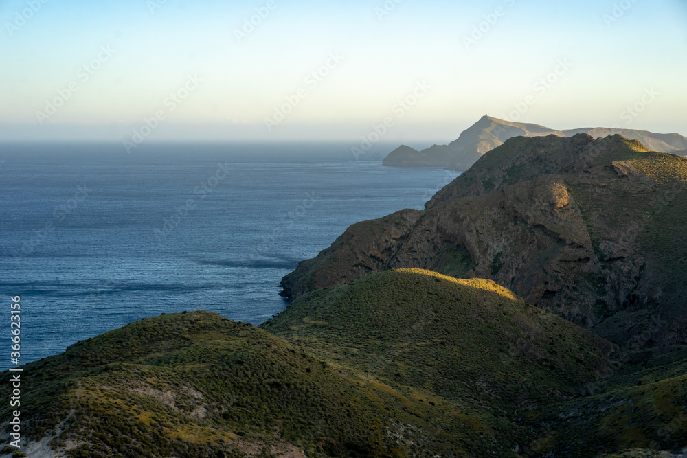 Scenic view of cliffs by seascape against clear sky at sunset