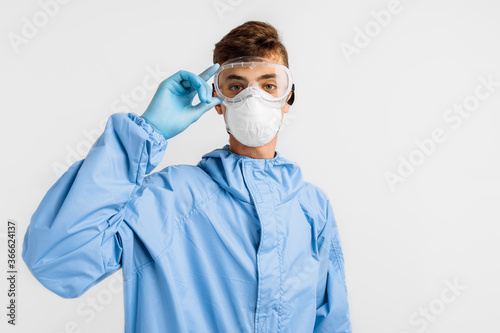 male doctor wears a protective suit to fight the covid-2019 coronavirus pandemic. Protective suit, safety glasses, gloves, respirator, on an white background
