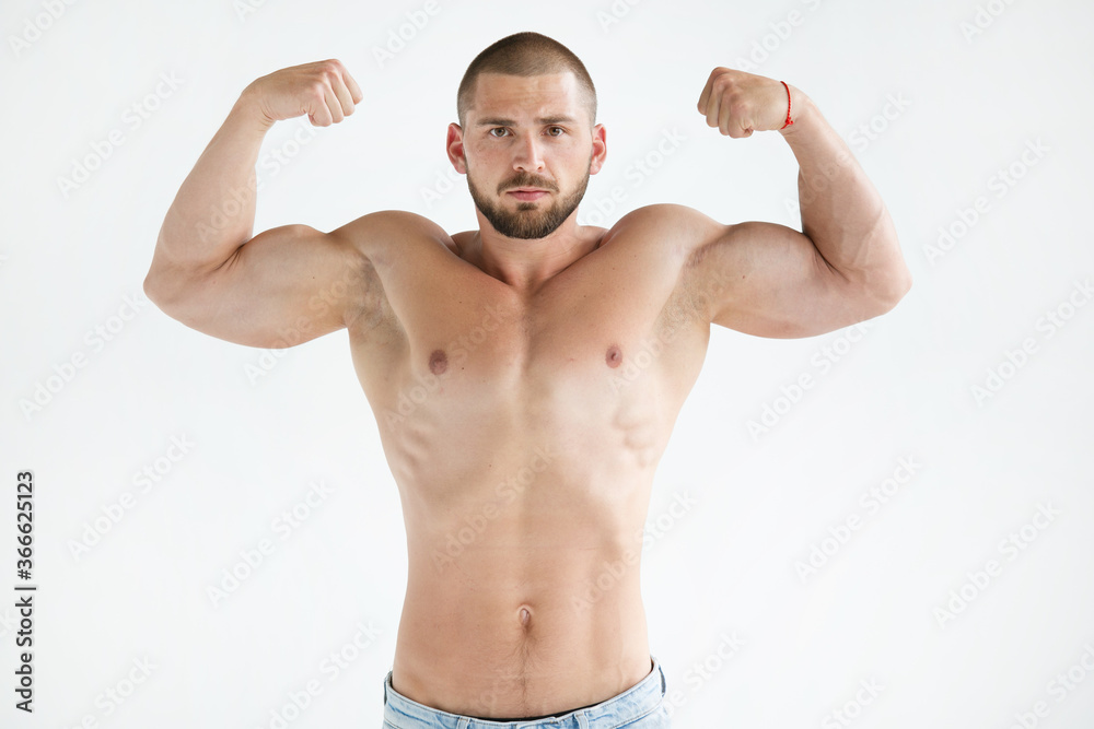 muscular young man showing his muscles. A man with a naked athletic torso poses in a photo studio on a white background. A healthy image of a strong, well-trained male body. Shows the muscles. muscular young man showing his muscles. A man with a naked athletic torso poses in a photo studio on a white background. A healthy image of a strong, well-trained male body. Shows the muscles.