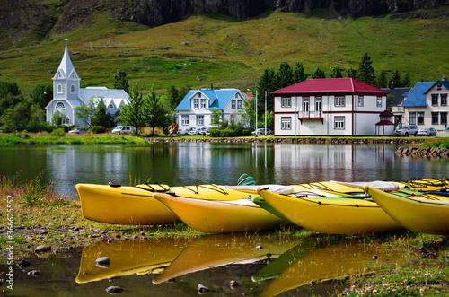 Yellow kayak boats with the Blue Church and houses in the background, Seydisfjordur, Iceland. Focus on the foreground.