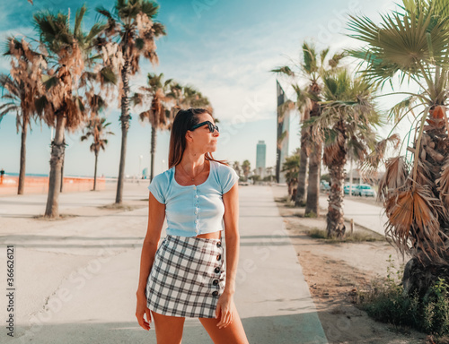 Beautiful young fashionable woman in sexy clothes posing in the green palm tree park. Summer concept photo