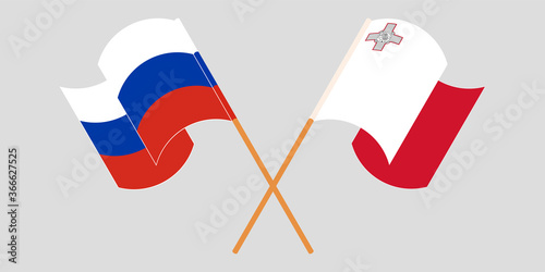 Crossed and waving flags of Malta and Russia