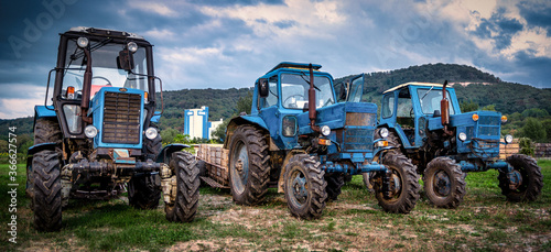 Dramatic view of three old farm tractors