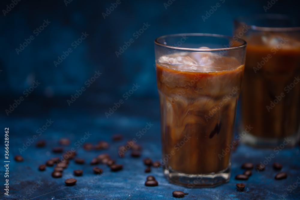 Cold summer drink, iced coffee with cream or milk.Cool drink with coffee grains on blue background Cold summer drink, iced coffee with cream or milk.Cool drink with coffee grains on blue background