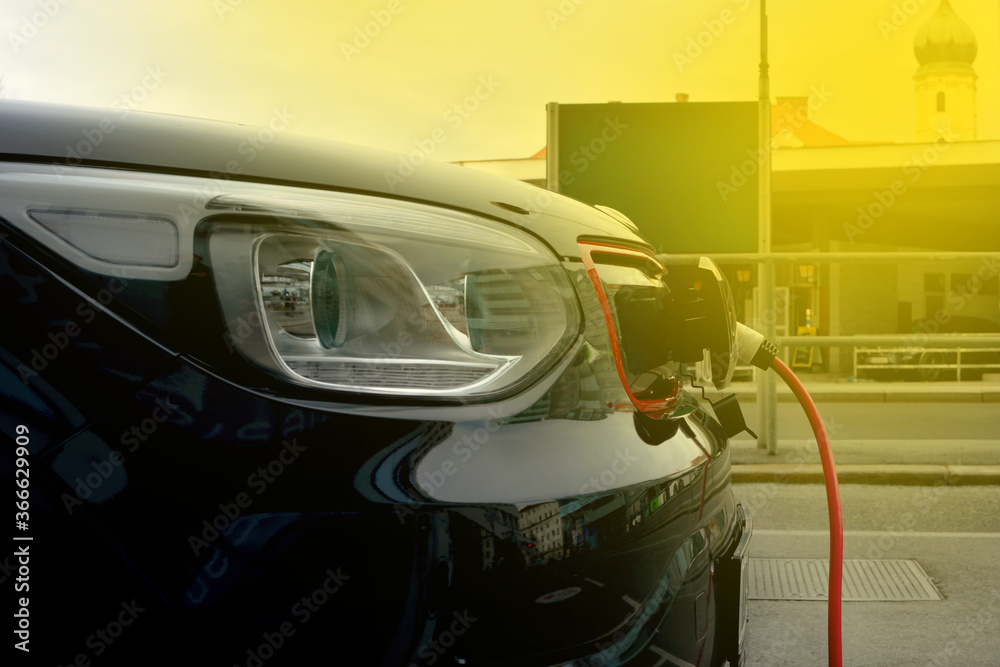 Obraz premium Modern electric car plugged in charging on the street station. New energy vehicles, environment friendly alternative energy for cars
