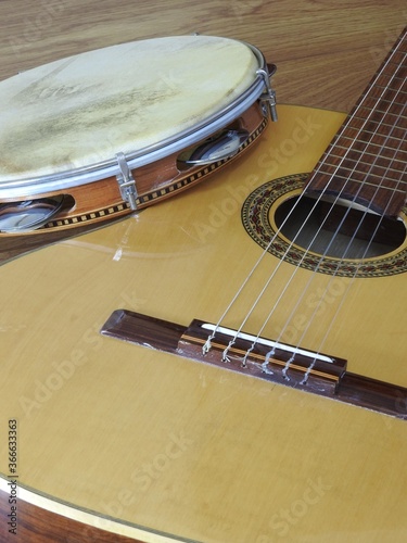 Close-up of an acoustic guitar and a pandeiro (tambourine), a Brazilian percussion musical instrument, on a wooden surface. They are widely used to accompany samba and choro music. photo