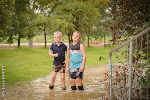 Boys playing in flooded creek with wet gumboots