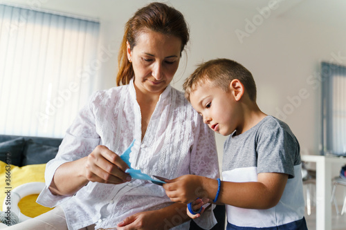 Front view on small caucasian boy 4 years old making decoration with mother - Little child playing with his mom learning new skills creative development at home in day - trust and support concept