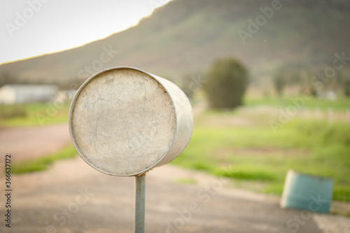 Round metal mailbox on country road with mountain in background