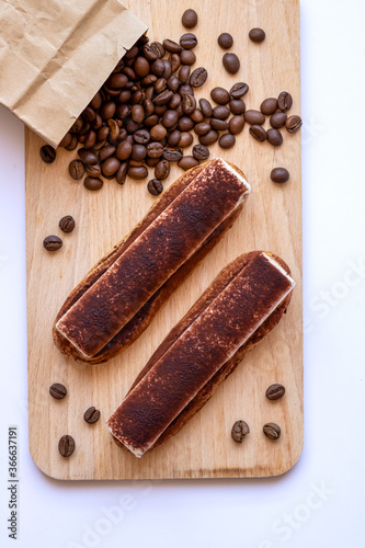 Top view on eclairs to wooden board with sprinkled coffee beans.
