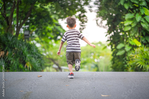 Back shot of young little boy running on a road
