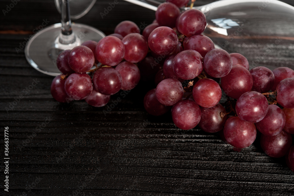 Bunch of red grapes and champagne glass with dark wood background Bunch of red grapes and champagne glass with dark wood background