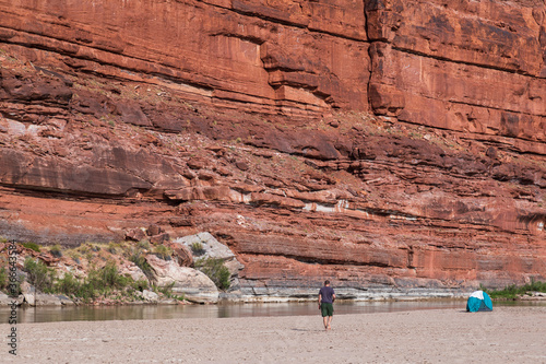 A man walks toward a tent in a Utah desert canyon along the Colorado River