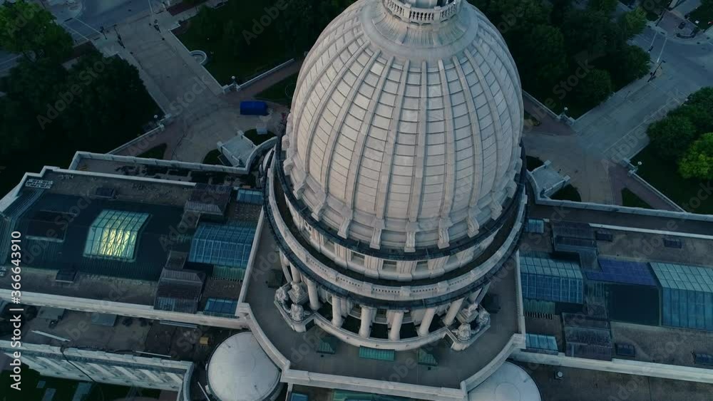 Low aerial drone shot of Wisconsin Capitol Dome during blue hour. The camera tilts down as it passes over the statue at the top of the dome.