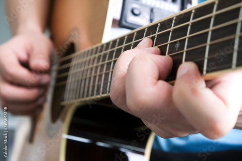 A man plays acoustic guitar at a resting room in his house.