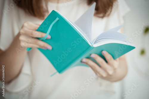 Beautiful young female hands holding and reading a book