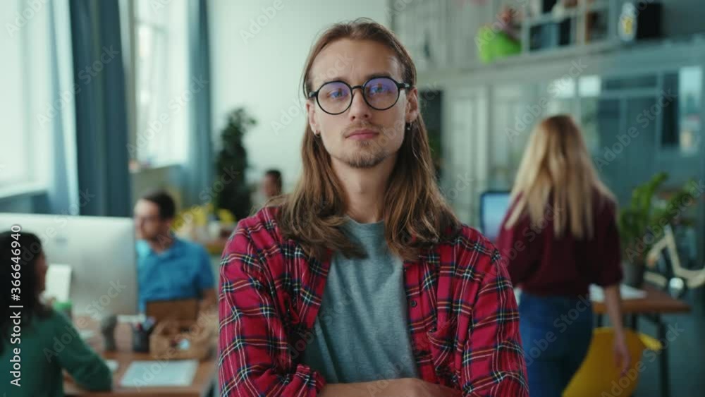 Portrait of handsome young confident businessman wearing glasses crossing arms in corporate room. Coworking center. Open space office.