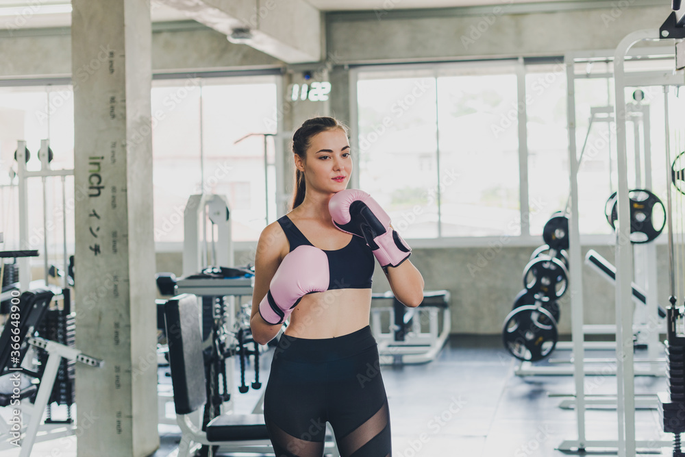 Beautiful girls exercise by boxing in the gym. She wears a pink boxing glove and wears exercise. Beautiful girls exercise by boxing in the gym. She wears a pink boxing glove and wears exercise.
