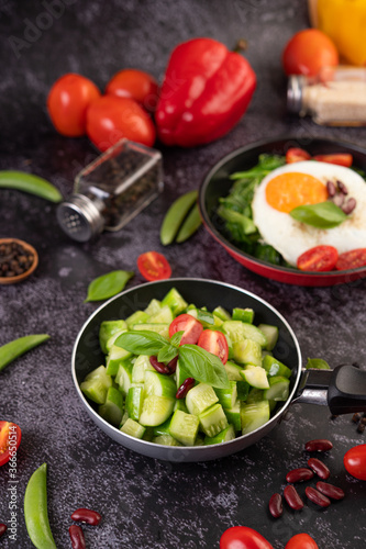 Cucumber stir-fried with tomatoes and red beans in a frying pan.