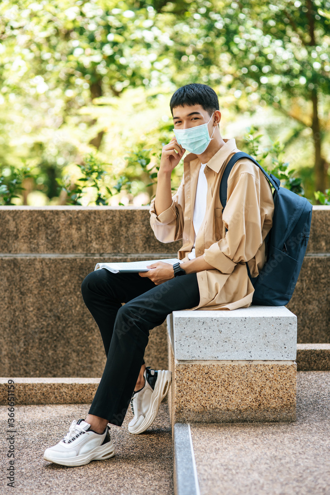 Obraz premium Men wearing masks sit reading books on the stairs.
