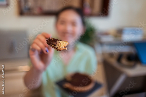 Obraz na płótnie Young pretty Asian woman eating delicious chocolate tart lying on bed w salonie