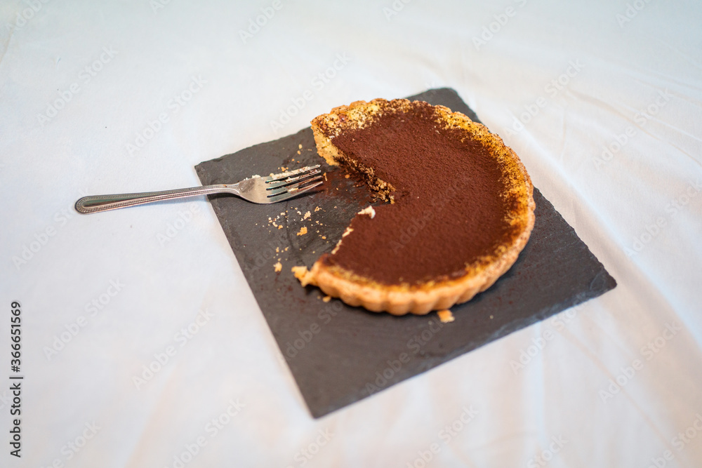 A top view of delicious chocolate tart half eaten on bed