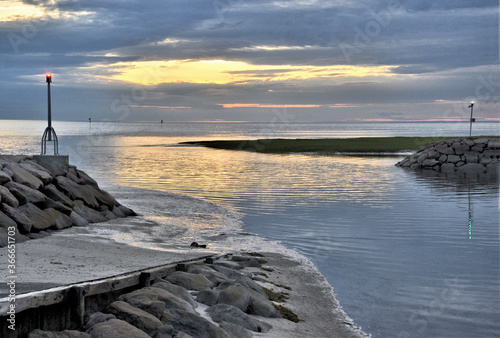 Lovely summer sunset casting warm reflections on ocean at entrance to Rock Harbor and boat ramp located in Cape Cod Bay, Orleans Massachusetts. photo