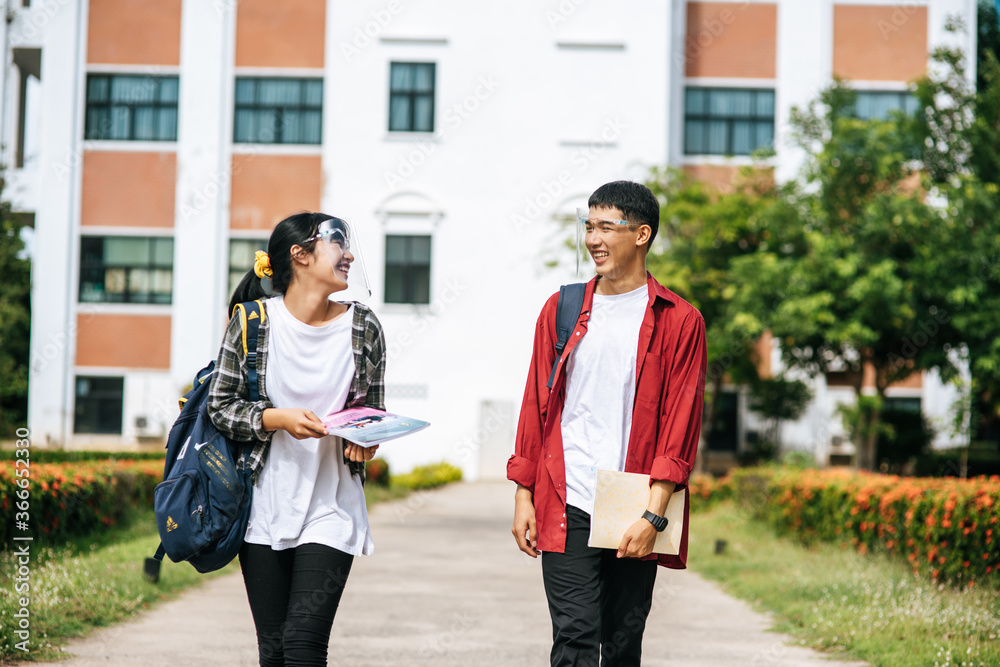 Obraz premium Male and female students wear a face Chill and stand in front of the university.