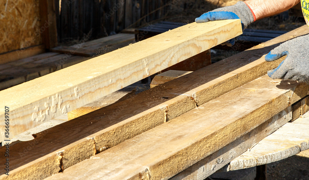 A worker shifts freshly sawn wooden planks. Preparation of building materials. A worker shifts freshly sawn wooden planks. Preparation of building materials.