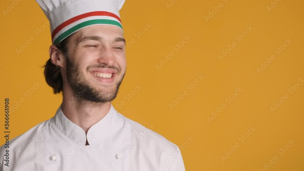 Handsome smiling professional chef in uniform happily looking aside on copy space over colorful background. Space for text Handsome smiling professional chef in uniform happily looking aside on copy space over colorful background. Space for text