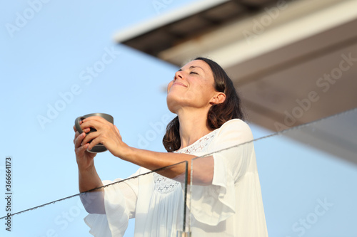 Leinwand Poster Adult woman with coffee cup breathing on a balcony