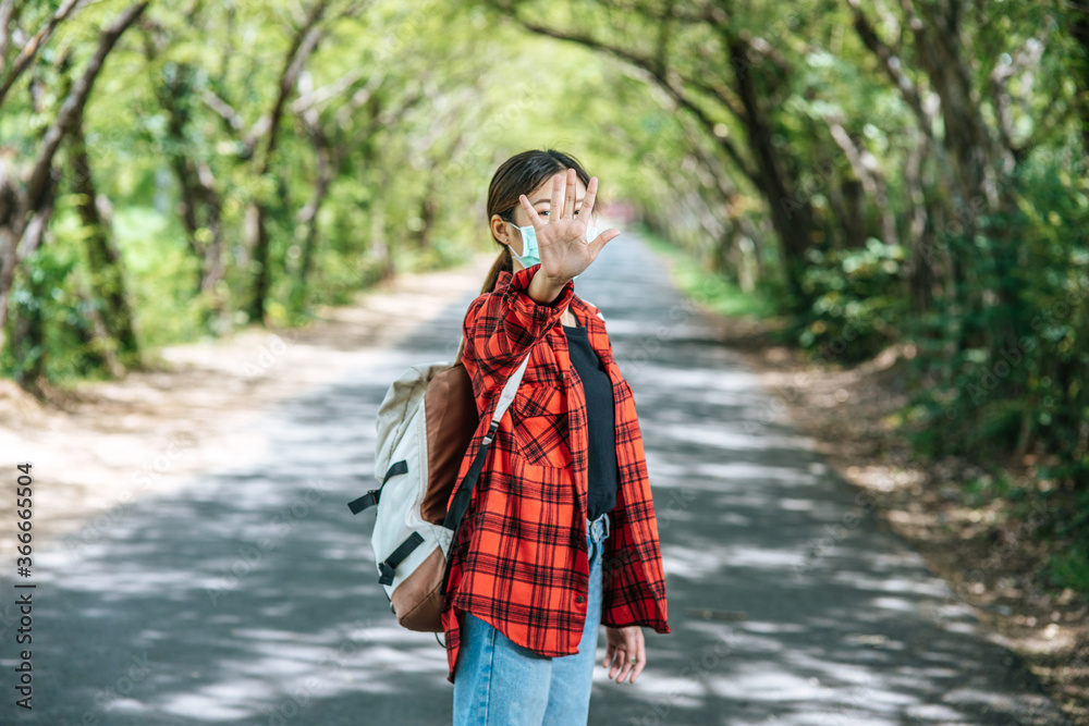 A female tourist carrying a backpack and raising her five fingers to ban on the road. A female tourist carrying a backpack and raising her five fingers to ban on the road.