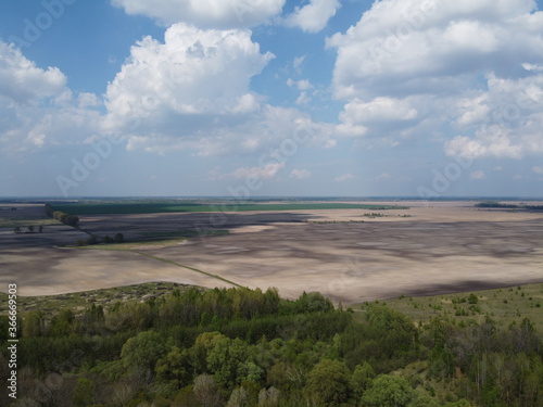 Fototapeta Naklejka Na Ścianę i Meble -  Beautiful blue sky over woodland, aerial view. Agricultural land.