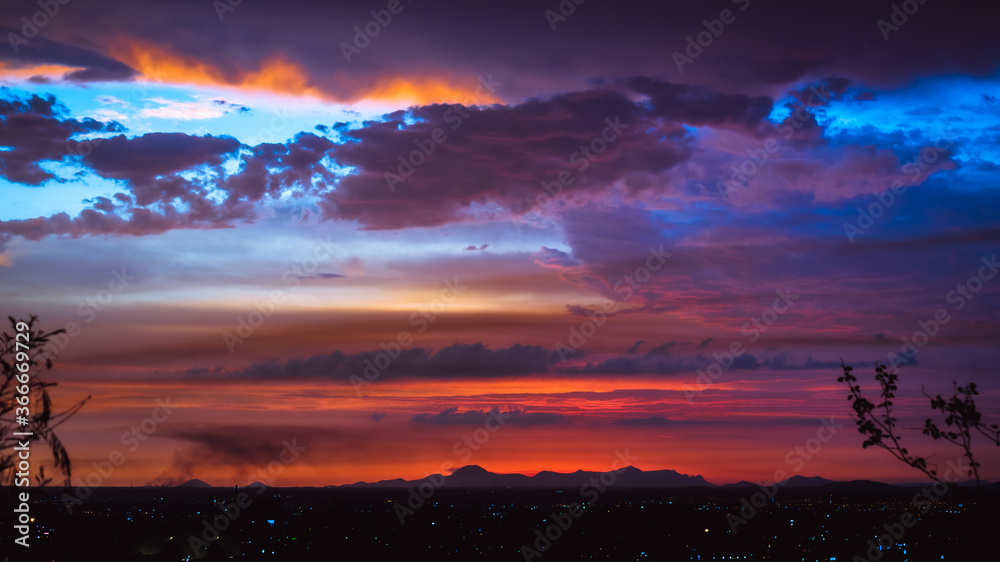 Obraz premium beautiful sunset with cloudy skies over the city and mountains 