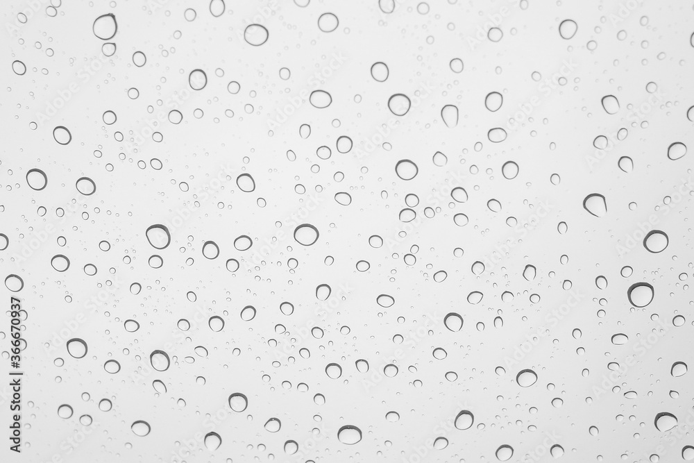water droplets on car glass during raining / closeup of clear raindrops on glass surface