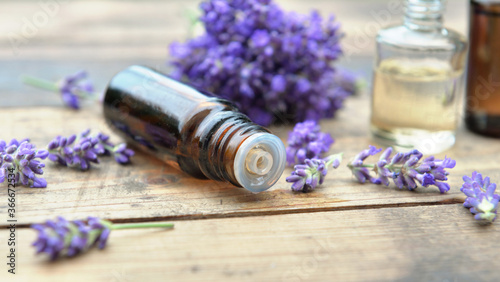 close on bottle of essential oil and bouquet of lavender flower arranged on a wooden