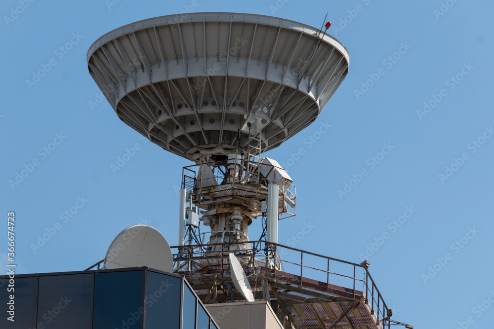 A large satellite dish is installed on the roof of the research building and is directed strictly up - into space A large satellite dish is installed on the roof of the research building and is directed strictly up - into space