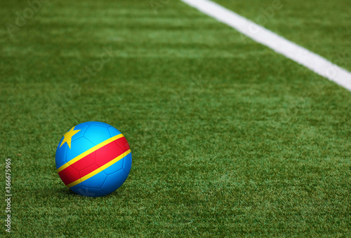 Congo flag on ball at soccer field background. National football theme on green grass. Sports competition concept.